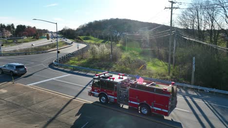 American-Fire-Engine-crossing-junction-in-city-with-waving-Flag-of-USA-on-top