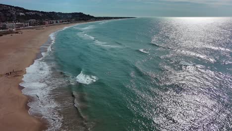 Port-ginesta-beach-with-shimmering-turquoise-waters-and-sandy-shore,-barcelona,-spain,-aerial-view