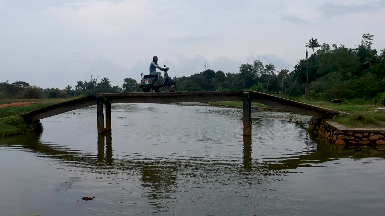 Motorbike rider crossing a village bridge,India,Crossing river ,Aerial shot
