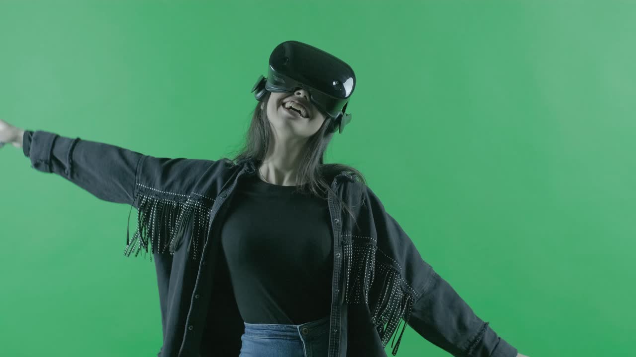 feliz joven hermosa mujer bailando en el auricular vr. casco de realidad virtual en el fondo verde. llave de croma