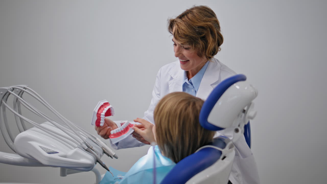 Dentist teaching little patient about oral care using dental model closeup