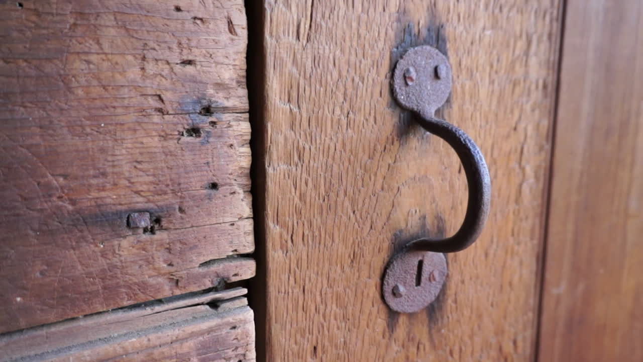 Detail of cast iron door handle and rustic wood panel in 18th century barn.