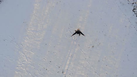 top down shot of a happy person spinning and dancing the arms and legs in the freshly fallen snow during winter