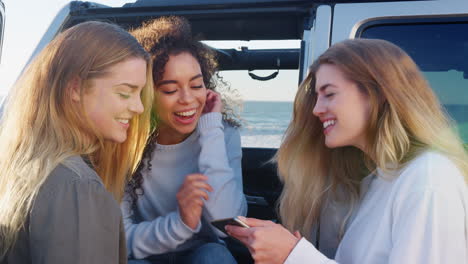 Junge-Erwachsene-Frauen-Auf-Roadtrip-Mit-Smartphone-Neben-Ihrem-Auto
