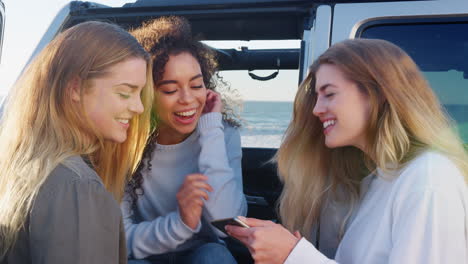 Mujeres-Adultas-Jóvenes-En-Viaje-Por-Carretera-Usando-Un-Teléfono-Inteligente-Junto-A-Su-Automóvil