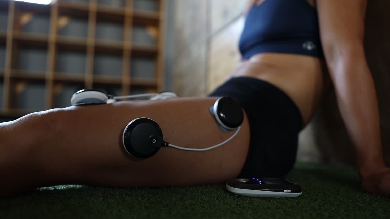 imágenes de primer plano de almohadillas de masaje de electrovibración que se utilizan en las piernas de un atleta