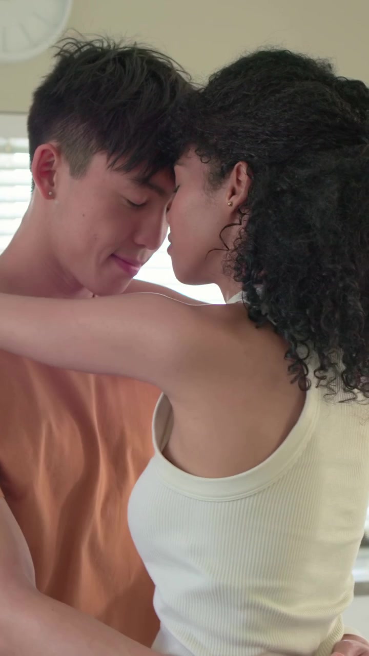 Vídeo vertical: Abraçando, mulher de regata abraçando homem de camiseta na cozinha perto de uma tigela, demonstrando amor