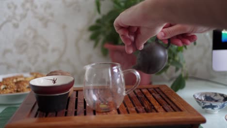 tea ceremony on a portable table. draining the first brew, rinsing the tea. in chinese, si cha, washing, which removes impurities from the surface of the tea, to fully develop the aroma.