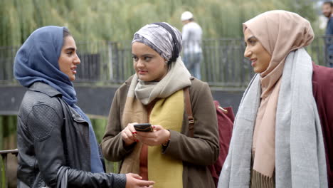 muslim female friends using mobile phone in urban setting