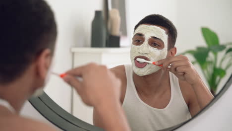 hombre negro guapo con máscara facial se cepilla los dientes