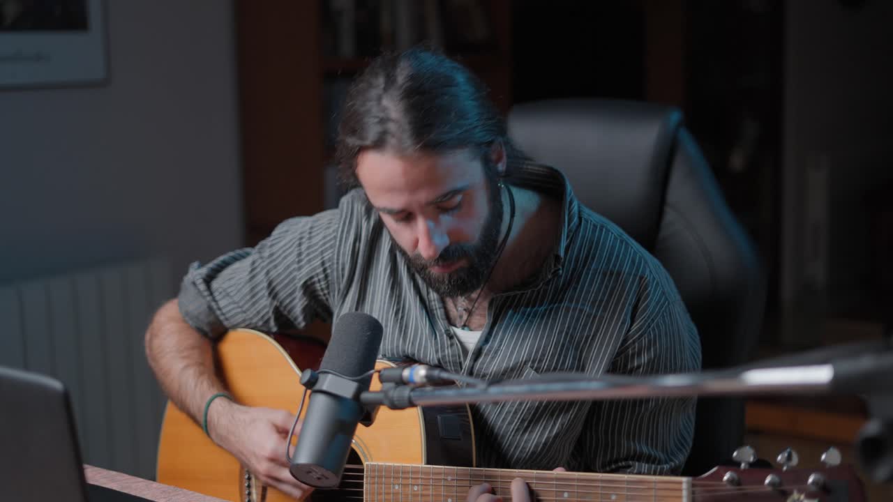 hombre tocando la guitarra acústica en el estudio casero