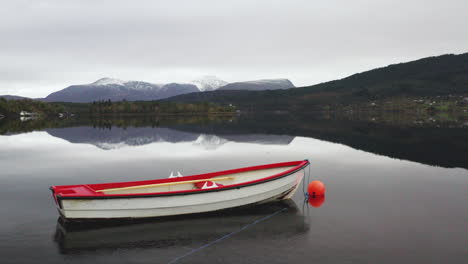 wooden boat reflected floating in a norwegian fjord - aerial drone shot