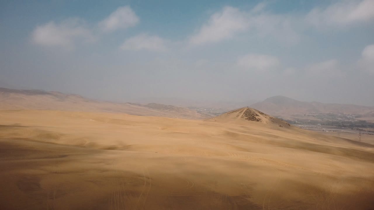 Vista aerea di camion fuoristrada che attraversano le dune di Ica, Perù - ripresa con drone in allontanamento.