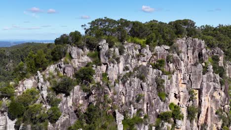 drone footage captures the rugged beauty of nimbin rocks, showcasing lush greenery and striking rock formations under clear skies