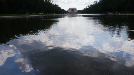 vista desde el agua hasta los escalones delanteros del monumento a lincoln tomada desde el estanque de reflexión con gente en primer plano
