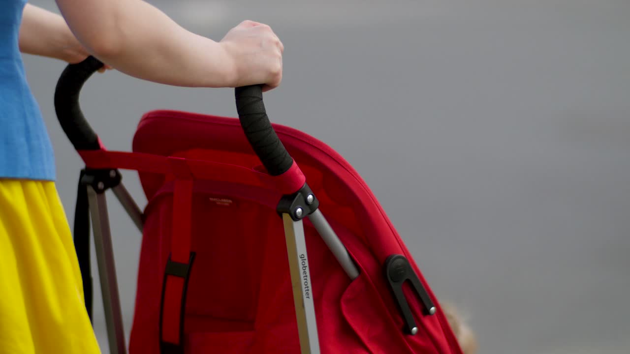mujer empujando un cochecito rojo en la calle
