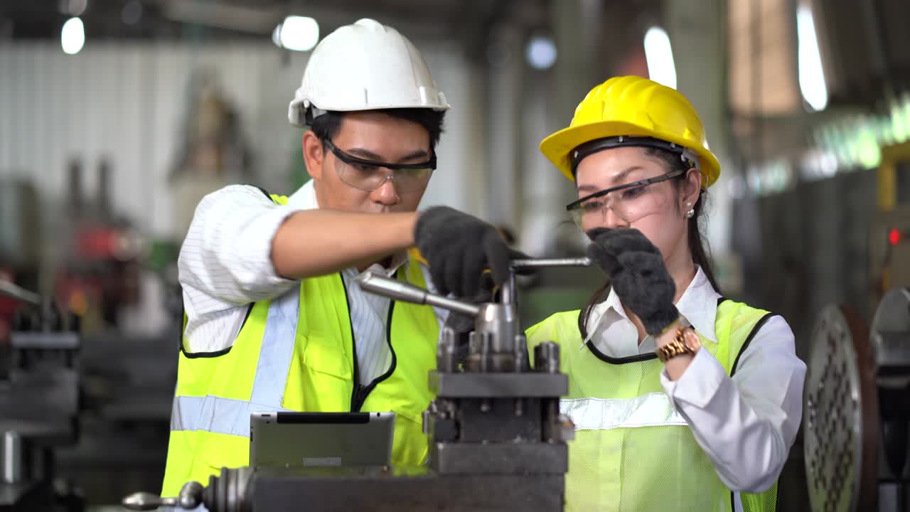 asian industrial Engineer manager man demonstration and training mechanic worker woman operating industrial lathe machine and checking with digital tablet in heavy industry manufacturing factory .