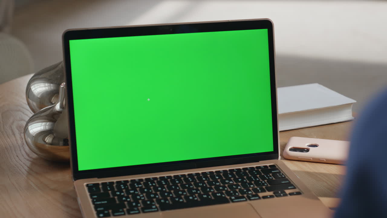 portátil con pantalla verde en la mesa de madera