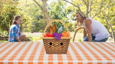Animation-of-picnic-basket-on-gingham-tablecloth-and-happy-caucasian-mother-and-daughter-in-park