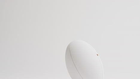 pelota de rugby blanca en patear tee en fondo blanco con espacio de copia, cámara lenta