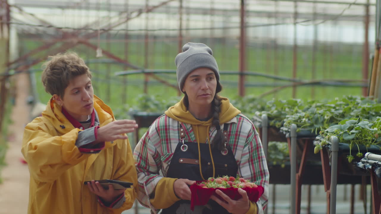 Female Coworkers Walking through Greenhouse Farm and Talking