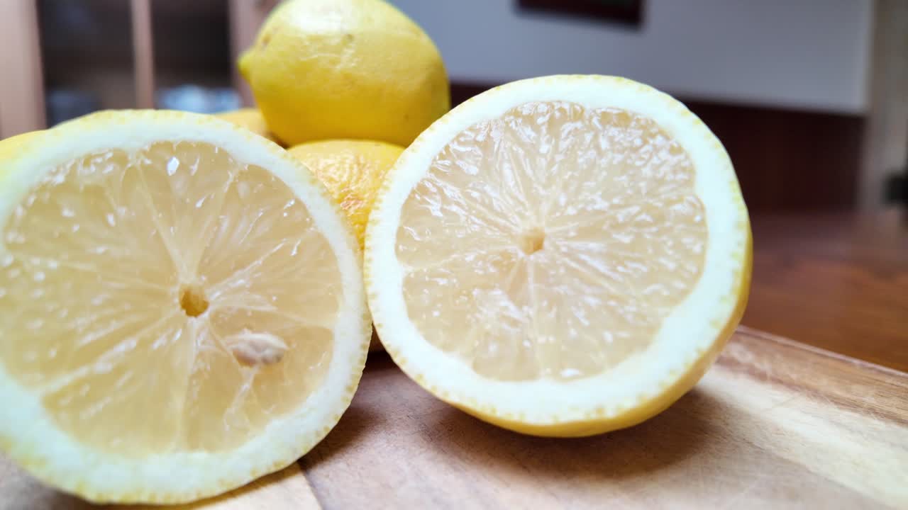 Fresh whole and sliced lemons on a wooden cutting board