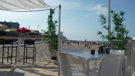a scenic view from a beach café overlooking the sandy beach, with children playing nearby. the scene captures the relaxed atmosphere of a sunny day at the beach, perfect for leisure and relaxation.