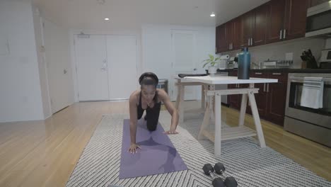 An-action-shot-of-a-black-female-doing-a-stretching-pose-in-front-of-her-lap-top-in-her-kitchen