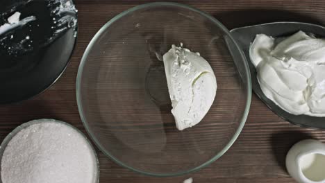 añadir ingredientes a un tazón de vidrio. manos masculinas haciendo postre. delicioso crema agria suave queso crema dulce. amasar los ingredientes. yogur casero natural fresco. relleno para eclairs. postre de cuajada.