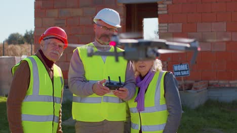 specialist worker fly on drone on building construction site, showing house to grandparents clients