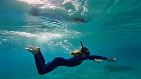 woman snorkeling and freediving in clear blue tropical waters