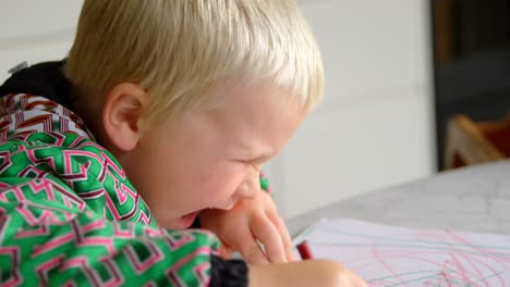 Boy-drawing-with-crayon-on-a-paper-at-home-4k