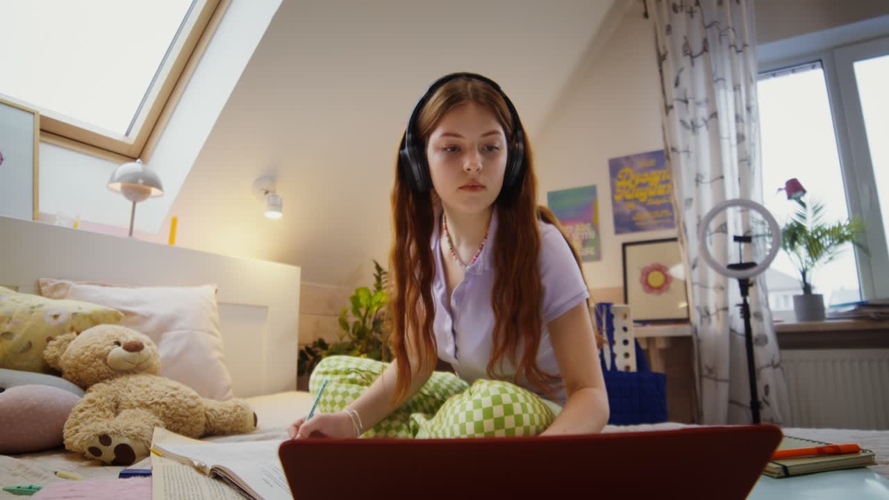 Teenage girl studying at home on her bed
