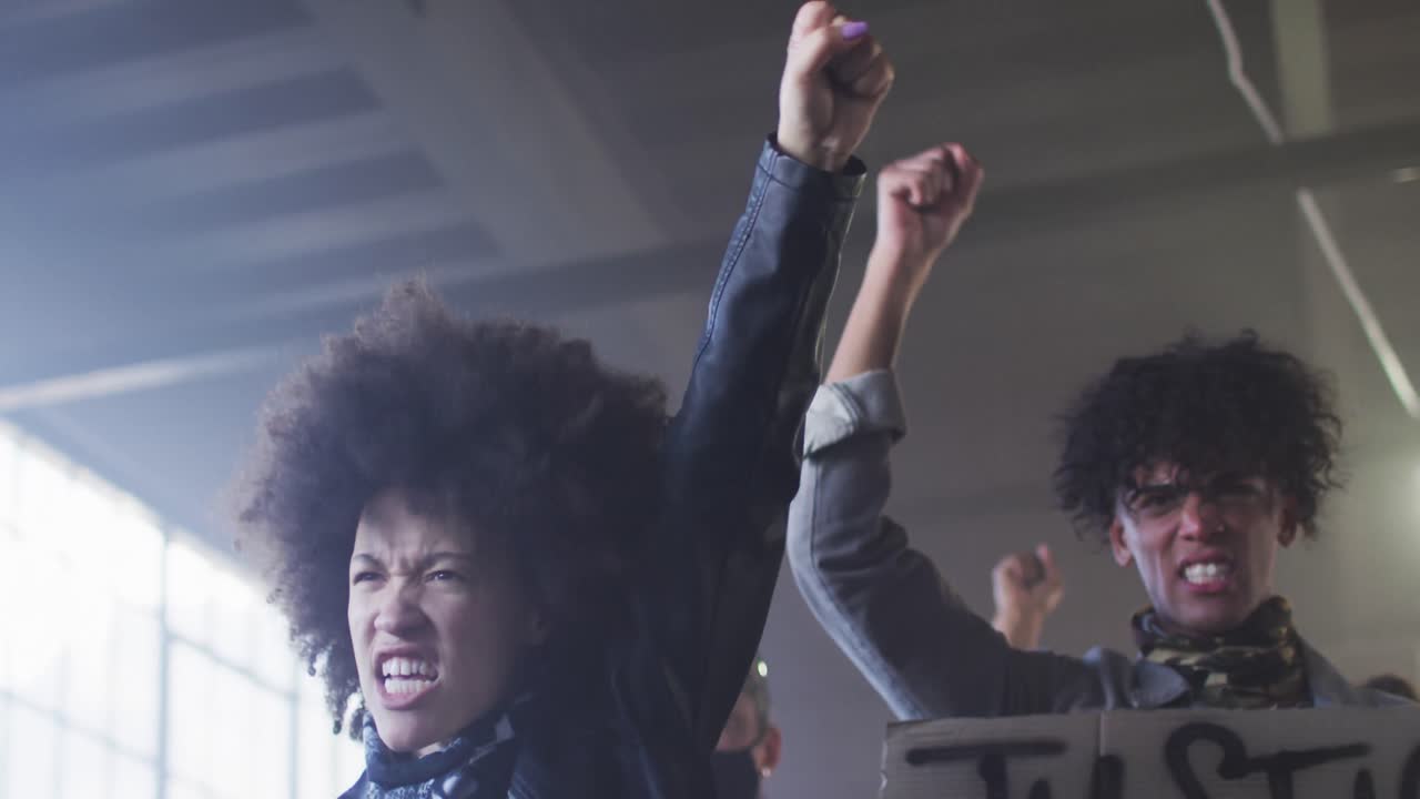 Diverse group of people wearing face masks holding protest signs shouting raising fists