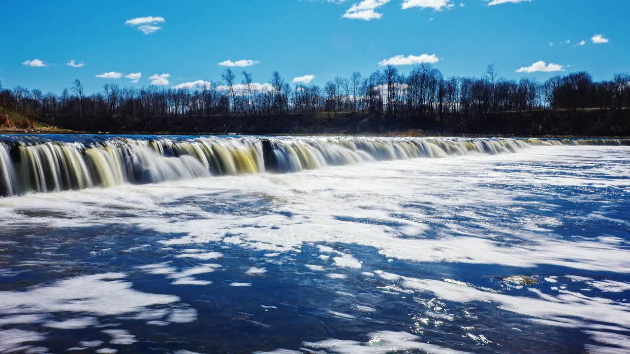 Widest natural waterfall in Europe flows over rocky ridge spring river timelapse