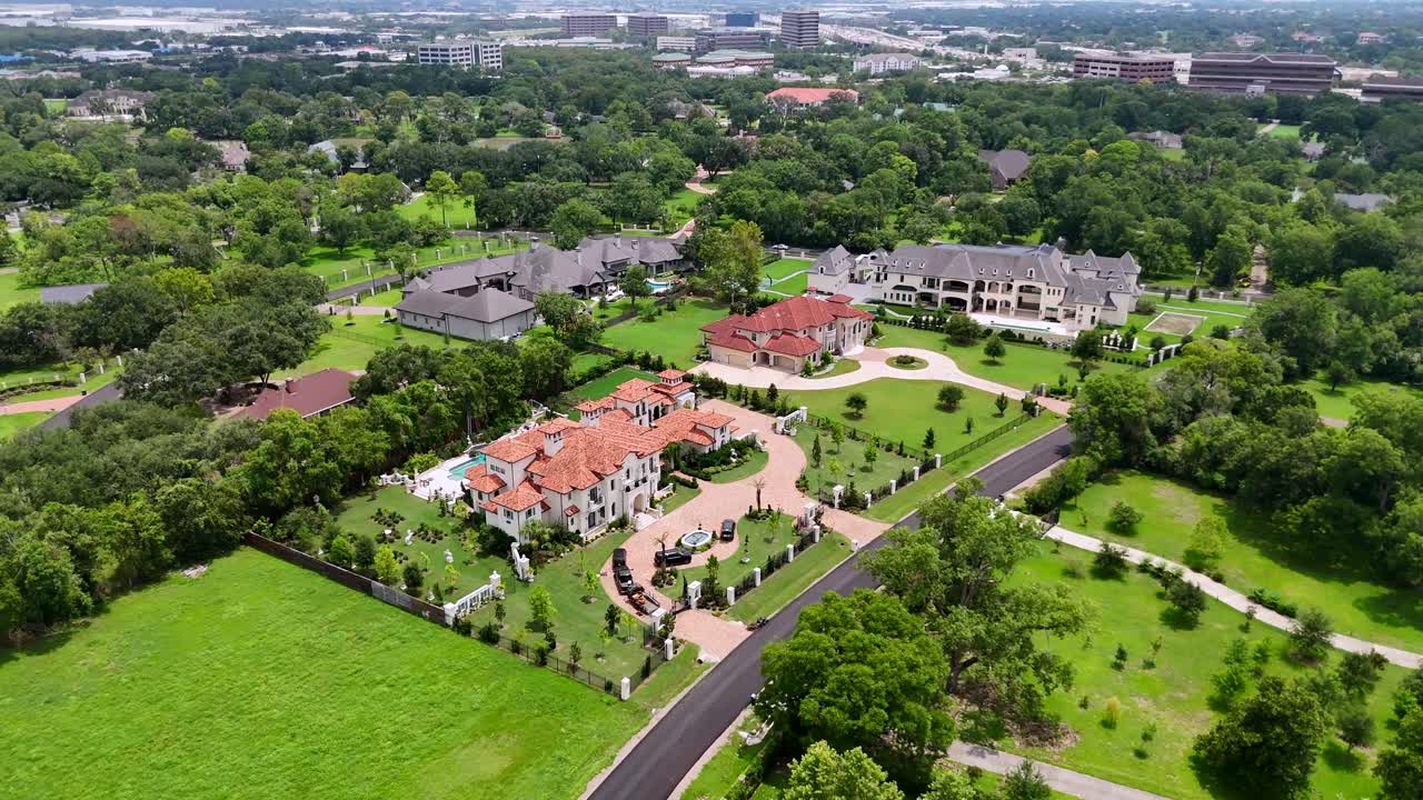 An aerial view of multiple mansions and estates, on a sunny day.