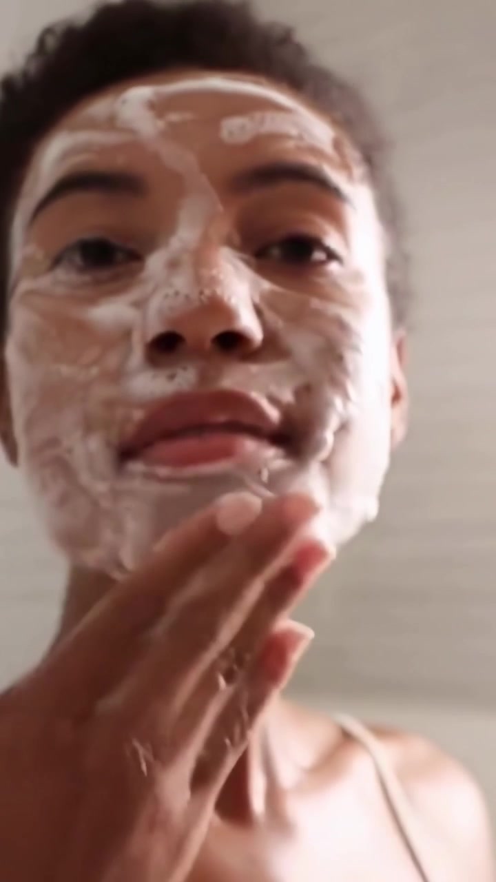 Young Woman Cleansing Her Face with Foamy Skincare Product
