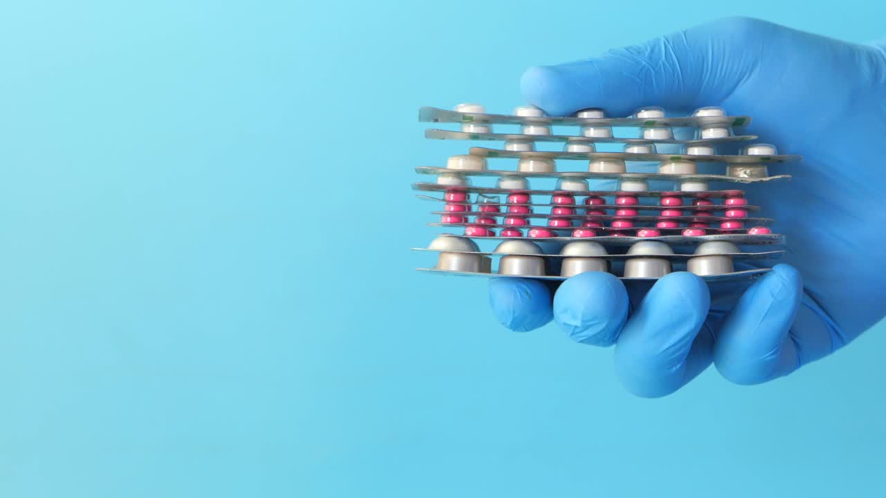 파란 장갑을 입은 손으로 쳐진 약 패키지를 들고