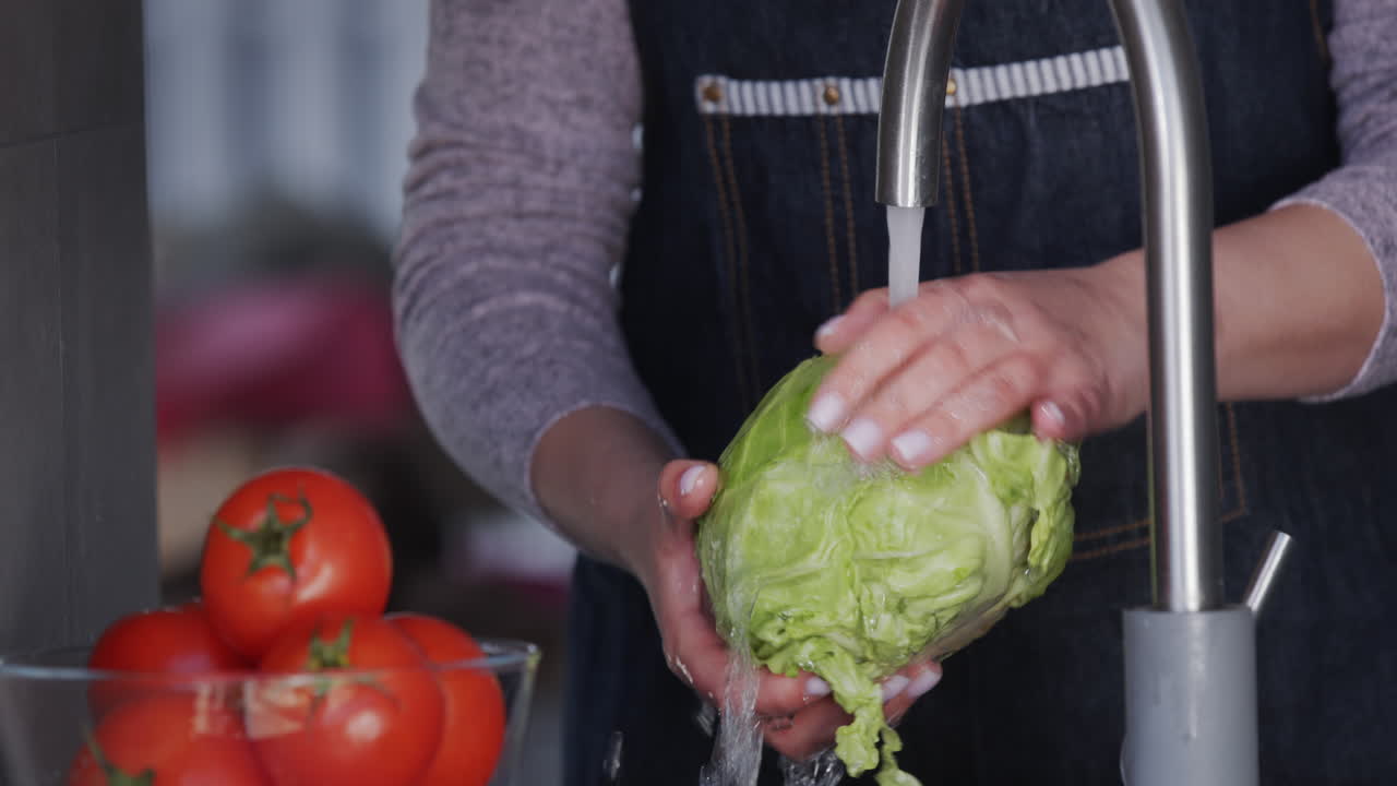Women's hands hold cabbage under a stream of water
