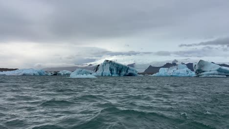 Vista-Desde-El-Barco-De-Muchos-Trozos-De-Hielo-Flotando-En-Una-Laguna-Glaciar-Volcánica