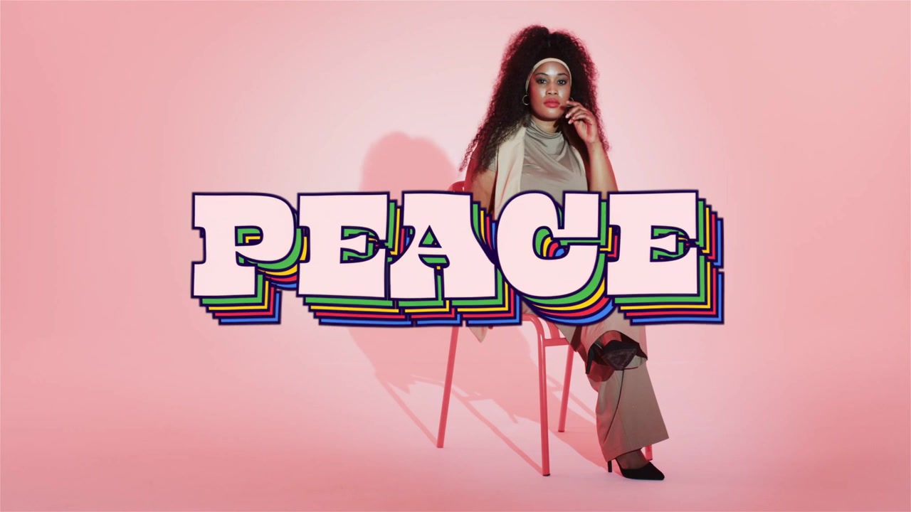 Model sidder klar under et "PEACE"-overlay, der dækker underkroppen, drejer hovedet og smiler til en modeoptagelse.