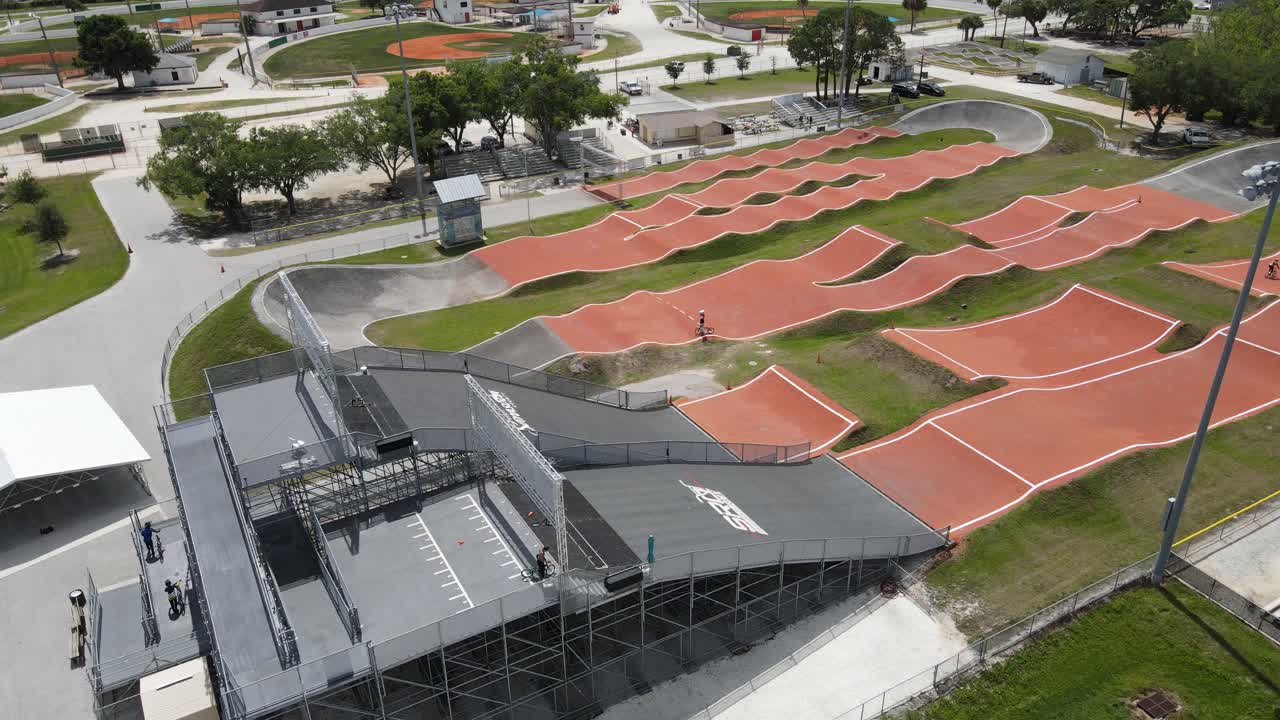 visão de drone de uma pista de bmx e um salto em distância de um ciclista após o lançamento a partir da rampa