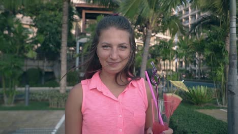 lady in beautiful pink dress stands against green palms