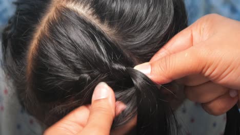 close-up of hands braiding dark hair