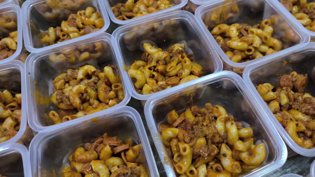 Cooked macaroni is portioned into small, equal containers. This method simplifies division, serving, or preparation for sale