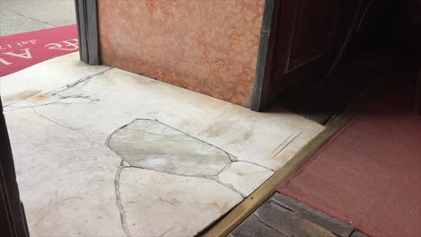 Waitress-step-on-the-ancient-marble-floor-on-the-entrance-of-historical-Caffà-Al-Bicerin-in-Turin