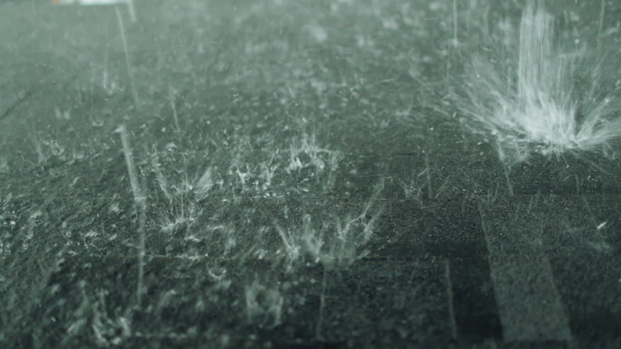 Heavy rain pours on the roof of a house made of soft shingles