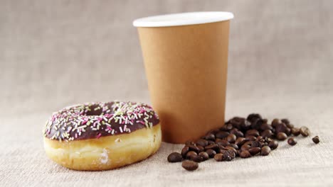 disposable coffee cup and chocolate doughnut and coffee bean with sprinkles