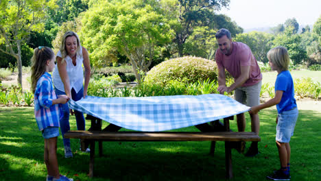 familia extendiendo el mantel en la mesa de picnic 4k