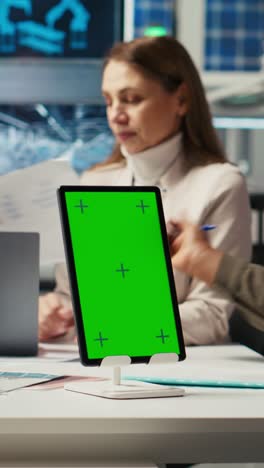 vertical video managers in office reviewing solar technology reports on isolated screen tablet